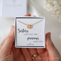 a woman holding up a box with a necklace on it that says sisters like you are preciouss and few