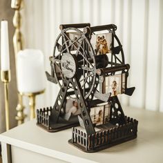 a ferris wheel with pictures on it sitting on top of a white table next to a candle