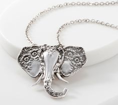 an elephant head pendant is shown on a chain with the word elephant written below it