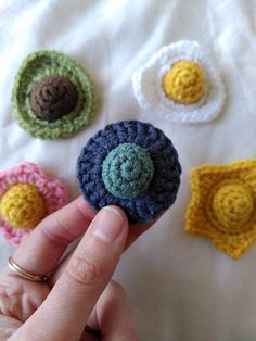 crocheted flower brooch sitting on top of a white blanket next to other crocheted flowers