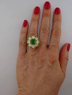 For Sale on 1stdibs - Sparkly and colorful cocktail ring that is a great addition to your jewelry collection. It is made of 18 karat (stamped) yellow gold and features a gorgeous Luxury Green Cluster Ring With Round Cut, Luxury Green Cluster Ring With Center Stone, Luxury Green Cluster Ring With Halo Setting, Luxury Green Diamond Ring Hallmarked, Luxury Green Cluster Ring For Formal Occasions, Luxury Green Cluster Ring For Formal Events, Luxury Hallmarked Green Diamond Ring, Luxury Green Hallmarked Diamond Ring, Luxury Green Cluster Ring For Anniversary