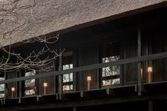 an outside view of a building with lights on the balcony and trees in the background