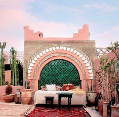 an outdoor area with potted plants and a table in front of a green gate