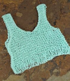 a crocheted top laying on the ground next to some rocks and stones,