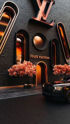 a black truck parked in front of a louis vuitton building with large letters on it