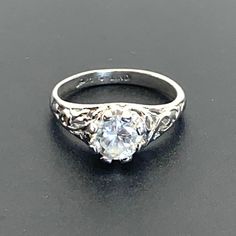 Vintage 925 Sterling Silver 1CT Sz Round Brilliant Cut CZ Scroll design ring with the center stone set in an 8-prong mounting   Ring Size 6.75 Weighs 2.76 grams  See all pictures for details and measurements excellent condition, minimal signs of wear may be present such as fine lines, scratches, dings visible using a jewelers loupe. Our Sterling Silver pieces have been acid tested to confirm purity and cleaned using a soft polishing cloth, or jewelers rouge, some patina be intentionally remaining  All of my jewelry comes packaged nicely for gift giving! Please visit my store / page to see my extensive inventory of fine, handmade, vintage to now and antique jewelry, all carefully tested and inspected Features: * Vintage, Elegant, Striking Size: Womens 6.75 Condition: Pre-Owned Like New like Classic Cubic Zirconia Birthstone Ring For Formal Events, Classic Cubic Zirconia Birthstone Ring For Formal Occasions, Classic Birthstone Ring With Prong Setting In Cubic Zirconia, Formal Solitaire Birthstone Ring In Sterling Silver, Classic White Topaz Ring With Prong Setting, Classic Promise Crystal Ring With Prong Setting, Classic Crystal Promise Ring With Prong Setting, Silver Cubic Zirconia Birthstone Ring For Formal Occasions, Classic Topaz Promise Ring