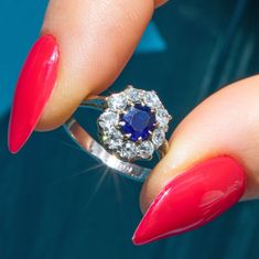 a woman's hand with red nails and a ring on her finger, showing the center stone