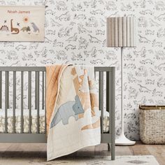 a baby's room with a crib, lamp and wallpaper in the background