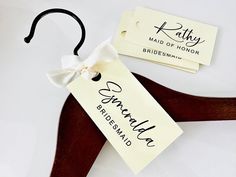 a wooden hanger with a name tag on it and a bow tie attached to it