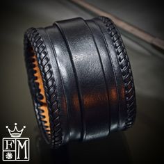 "This Black leather cuff is 2\" wide and hand dyed in a sleek black finish. It is hand braided along the edges with kangaroo lace and also features a hand tooled beveled ridge. A 3/4\" strap is woven through center and closes with leather covered snaps! Custom sized for your wrist! -2\" wide -Vegetable tanned leather -fully lined -Handmade in New York Thanks! Freddie" Luxury Adjustable Braided Leather Bracelets, Luxury Adjustable Leather Braided Bracelets, Handmade Black Leather Braided Bracelet, Black Leather Cuff Bracelet For Formal Occasions, Leather Cuff Bracelets With Black Band, Adjustable Black Hand Tooled Bracelet, Formal Black Leather Braided Bracelets, Formal Black Leather Cuff Bracelet, Leather Cuff Bracelet For Formal Occasions