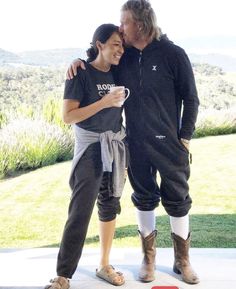 a man and woman standing next to each other in front of a lush green field