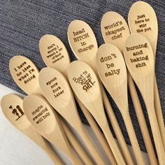 six wooden spoons with sayings on them sitting next to a blue and white cloth