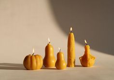 three candles are arranged in the shape of pumpkins and corn on the cob