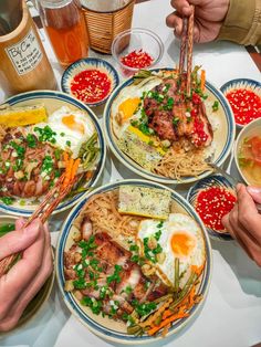 four plates of food with chopsticks sticking out of them, on a table