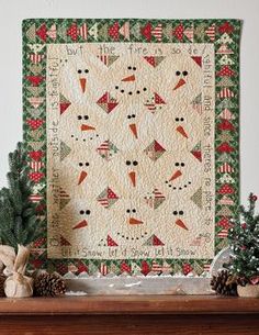 a quilted christmas wall hanging on a mantle with pine cones and fir trees in the foreground