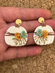 a pair of white pumpkin earrings with flowers on them