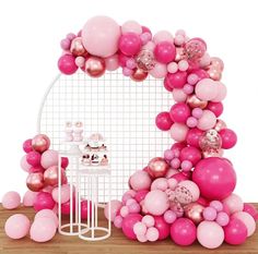 a pink and gold balloon arch on a table