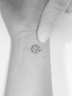 a small wrist tattoo with the earth on it's left hand and an arrow in the middle