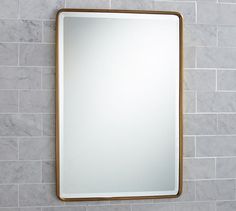 a bathroom mirror mounted to the side of a wall next to a tiled counter top