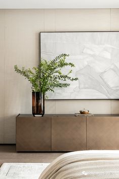 a plant in a vase sitting on top of a wooden cabinet next to a painting