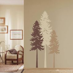 a living room with a chair and wall decals on the walls that have trees painted on it