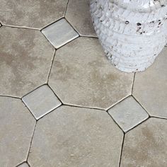 a white vase sitting on top of a tiled floor