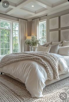 a large white bed sitting in a bedroom next to two windows