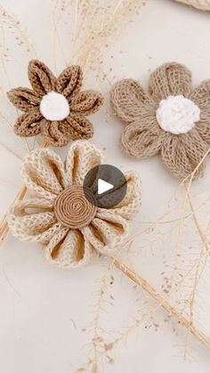 three crocheted flowers are sitting on top of each other, one is brown and the other is white