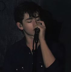 a young man holding a microphone up to his face and singing into it's mouth