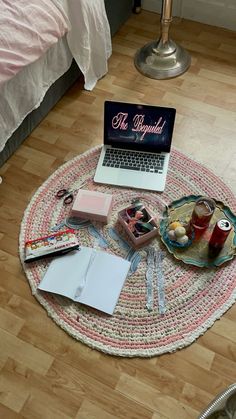 a laptop computer sitting on top of a wooden floor next to a plate of food