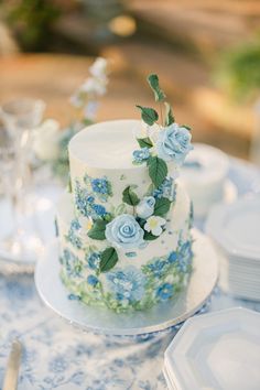 a white and blue cake sitting on top of a table next to silverware, plates and utensils