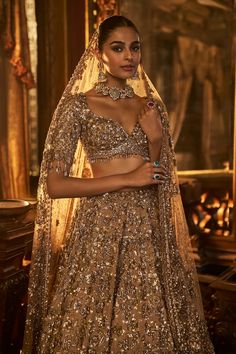 This lehenga set features heavy embroidery in tones of antique gold on a matching tissue silk base. The elbow sleeve blouse shows tassels at the waist as well as the sleeve hem. It is paired with matching heavily embroidered net dupattaFrom Seema Gujral's Falaknuma collection. DELIVERY TIMEPlease allow 8-12 weeks for your outfit to arrive. FABRIC DETAILSLehenga & Blouse - Tissue Silk Dupatta - Net Professional cleaning only. Glamorous Tissue Silk Sets With Zari Work, Glamorous Tissue Silk Lehenga With Zari Work, Glamorous Tissue Silk Sets With Dupatta, Glamorous Gold Sets With Intricate Embroidery, Glamorous Gold Lehenga With Resham Embroidery, Diwali Glamorous Tissue Silk Lehenga, Glamorous Gold Sharara With Intricate Embroidery, Glamorous Gold Choli With Intricate Embroidery, Glamorous Gold Sets With Zari Work