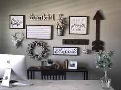 a white desk topped with a laptop computer next to a wall covered in framed pictures