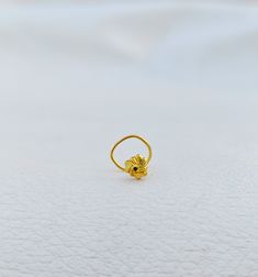 a gold ring sitting on top of a white surface with a small yellow object in the middle