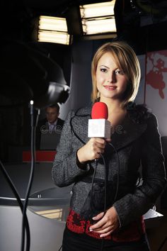 a woman is holding a microphone in front of a camera and another man behind her