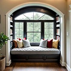 a window seat with pillows on it in front of a bookshelf