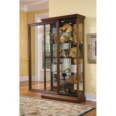 a large display case with glass doors in the middle of a floored room next to a rug