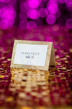 a place card holder sitting on top of a table covered in gold confetti