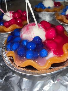 red, white and blue desserts are sitting on tin foil with candles in them