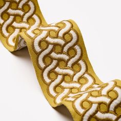 a yellow and white ribbon with an intricate design on it's side, against a white background