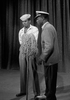 two men standing next to each other in front of a curtain