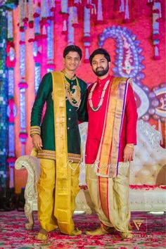 two men standing next to each other in front of a stage with flowers on it