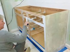 a woman is working on an unfinished cabinet