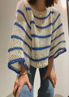 a woman is standing in front of a mirror with her hand on her hip and wearing a blue and white striped sweater