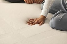 a woman laying on top of a bed with her hands resting on the mattress cover