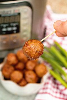 a person holding a skewer of tater tots in front of an instant pot