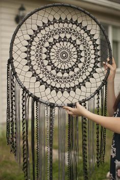 a woman holding up a black and white dream catcher