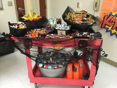 a red cart filled with lots of candy and halloween decorations on top of a white floor