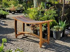 a wooden bench surrounded by potted plants in a garden area with gravel and rocks