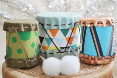 there are three different colored drums sitting on the table next to each other, and one has cotton balls in front of it